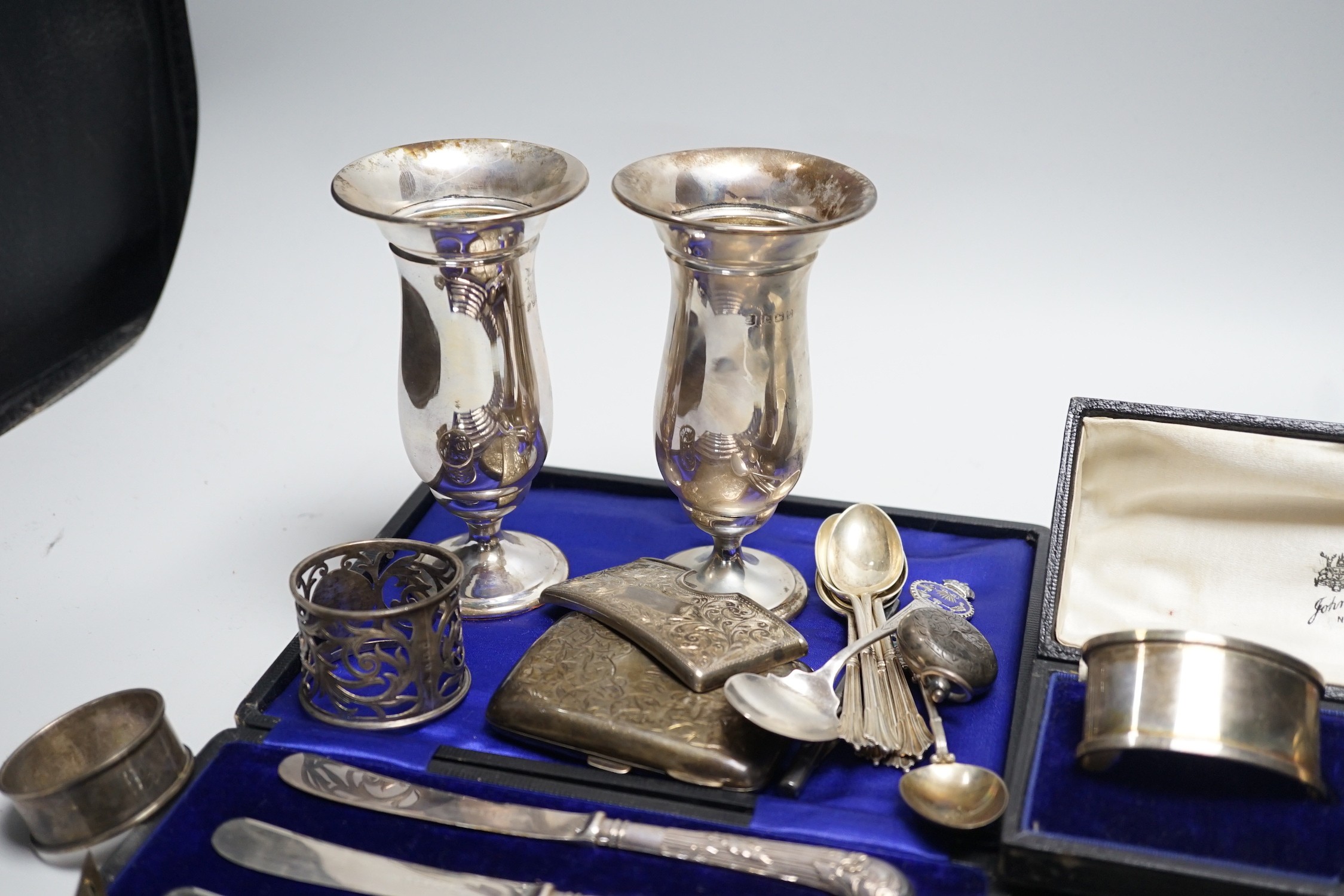 A mixed group of assorted silver ware including a pair of vases, 13.1cm, weighted, cased and loose napkin rings, cased teaspoons, cased silver pistol handled tea knives, sovereign case, mother of pearl handled fruit knif